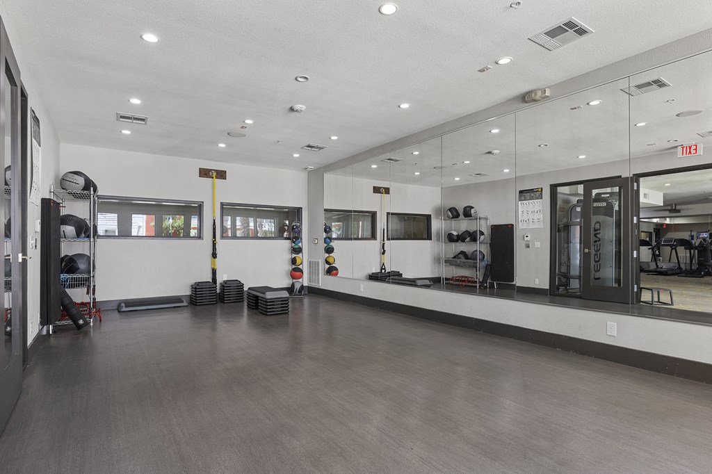a fitness room with mirrors and mirrors on the walls and a gym floor with weights