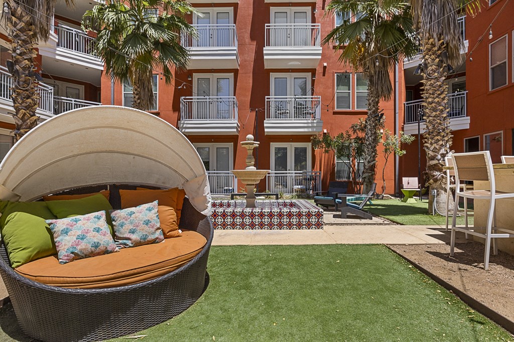a round swing in the middle of a lawn with a building in the background