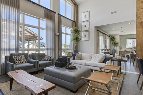 a living room with couches and chairs and large windows