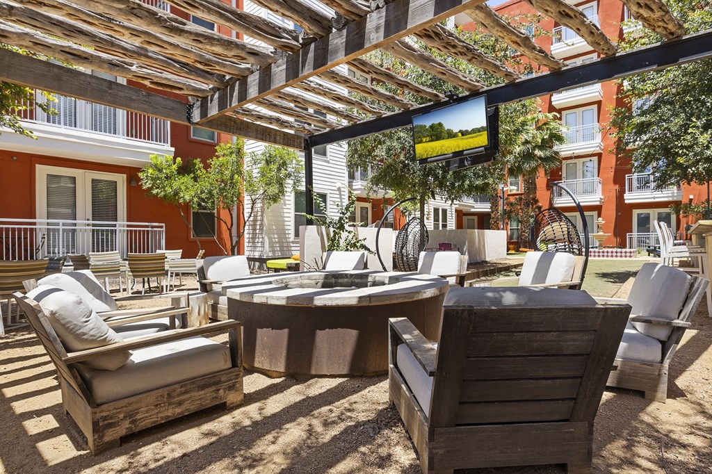 a patio with chairs and tables and a tv on a pergola