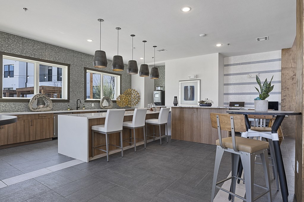 a kitchen with a bar and stools and a dining area