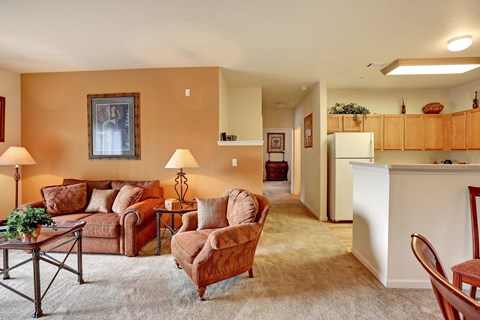 A living room with a brown sofa and a white refrigerator in the background.