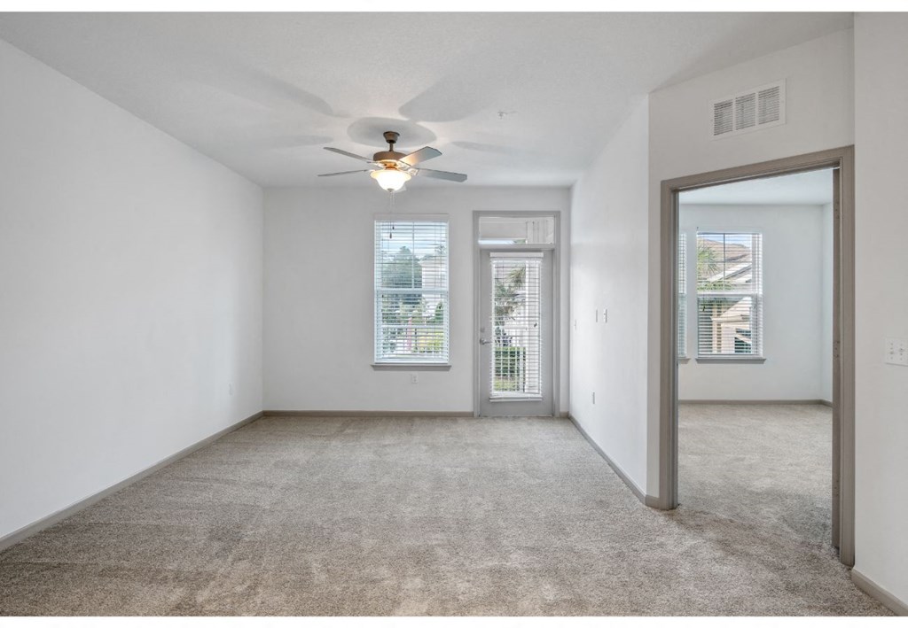 an empty living room with a ceiling fan and a window