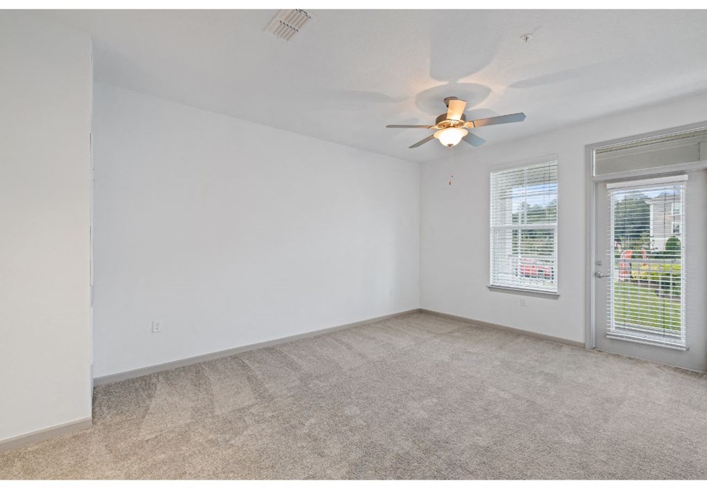 an empty living room with a ceiling fan and a window