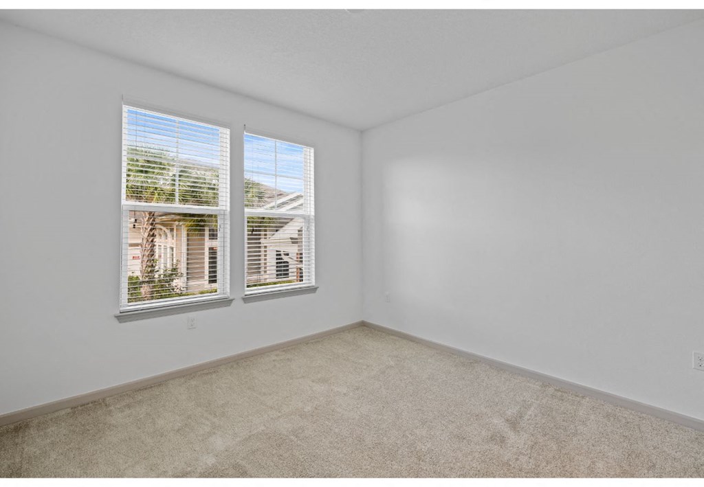 a bedroom with two windows and a carpeted floor