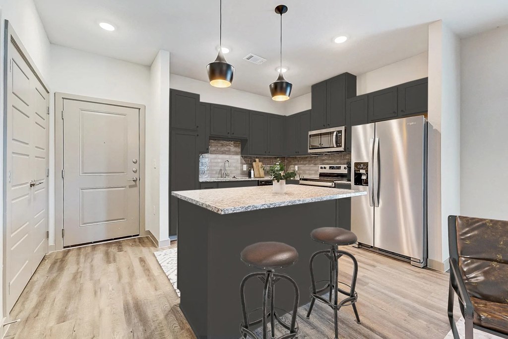 a kitchen with a bar and a stainless steel refrigerator