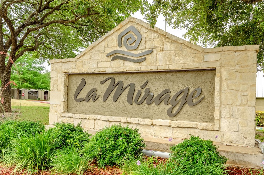 a sign for la mirage in front of some trees