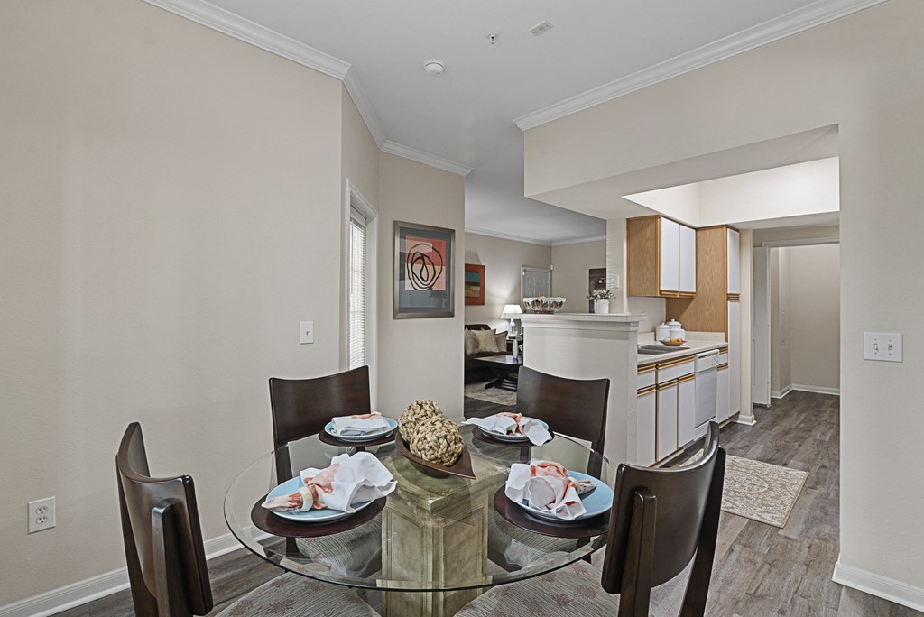 a dining room with a glass table and chairs and a kitchen