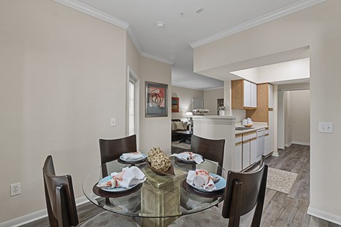 a dining room with a glass table and chairs and a kitchen