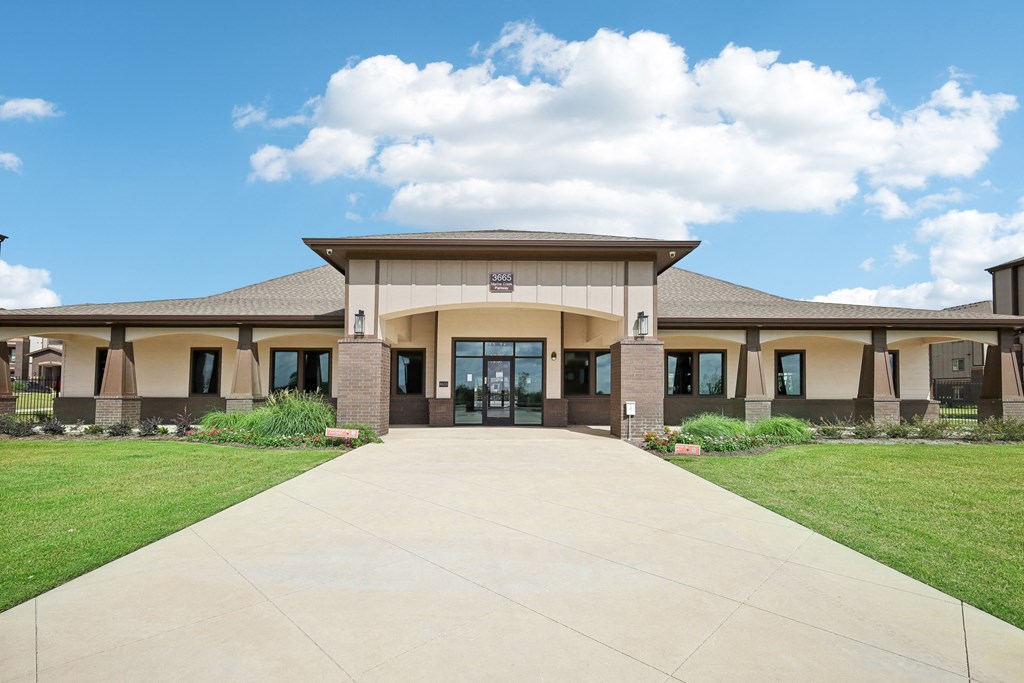 the front of a building with a walkway and grass