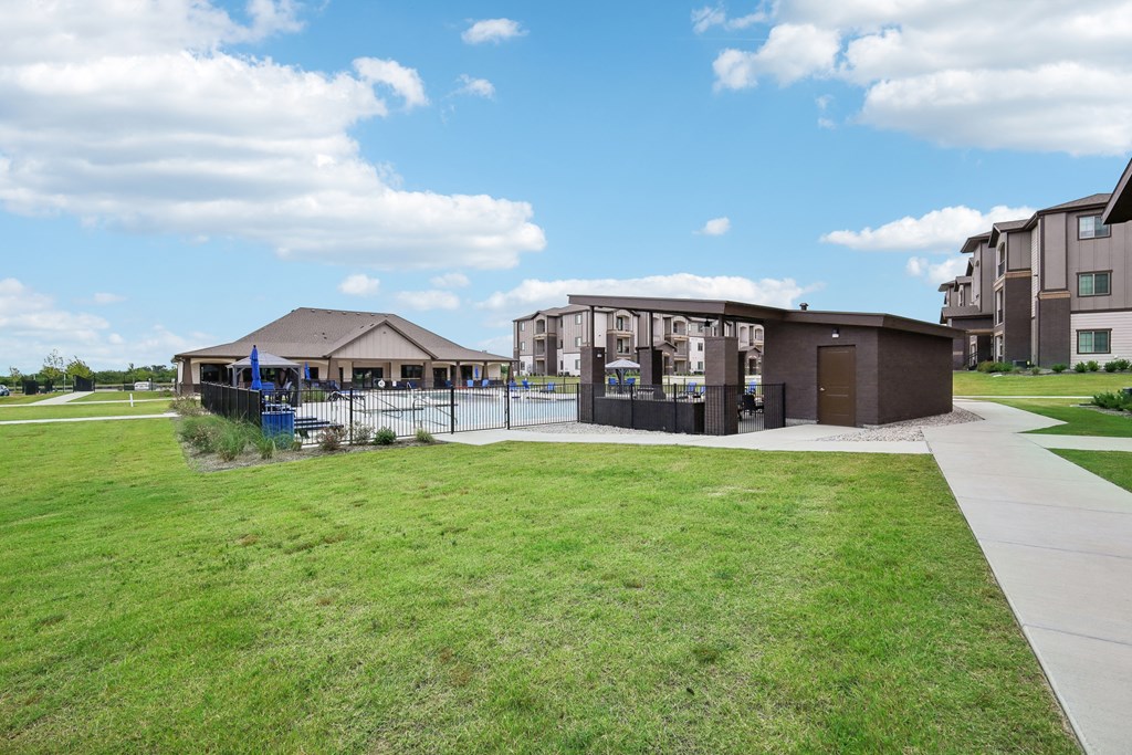 a building with a pool in front of a grassy field