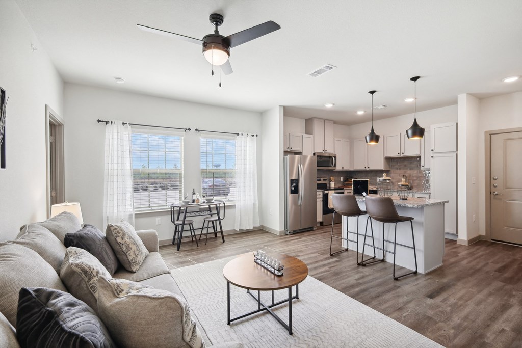 a living room with a couch and a table in front of a kitchen