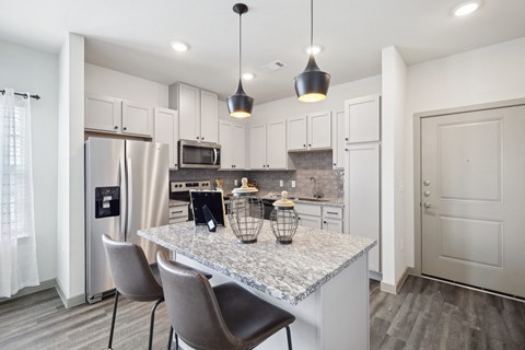 a kitchen with white cabinets and a marble counter top