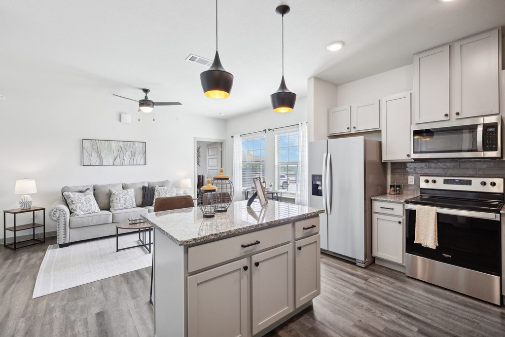 an open kitchen and living room with a marble counter top