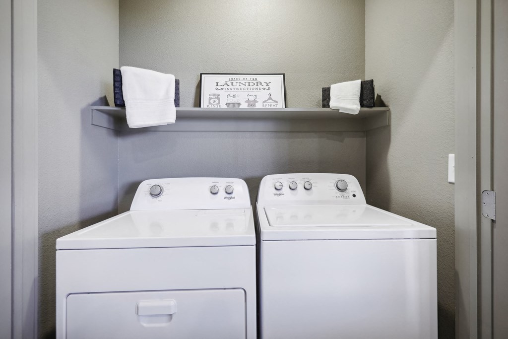 a washer and dryer in a laundry room with a shelf on the wall