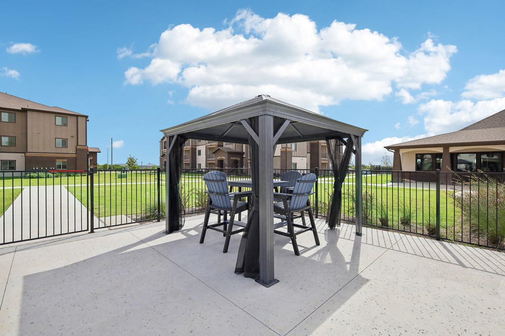 a patio with a table and chairs under a gazebo