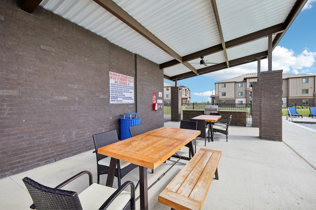 an outdoor patio with tables and chairs and a brick wall