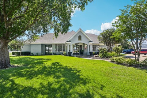 the front of a house with a lawn and trees