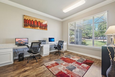 a home office with two desks and a large window