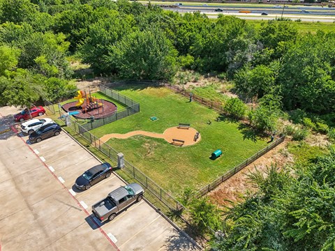 a park with a playground and cars parked in a parking lot
