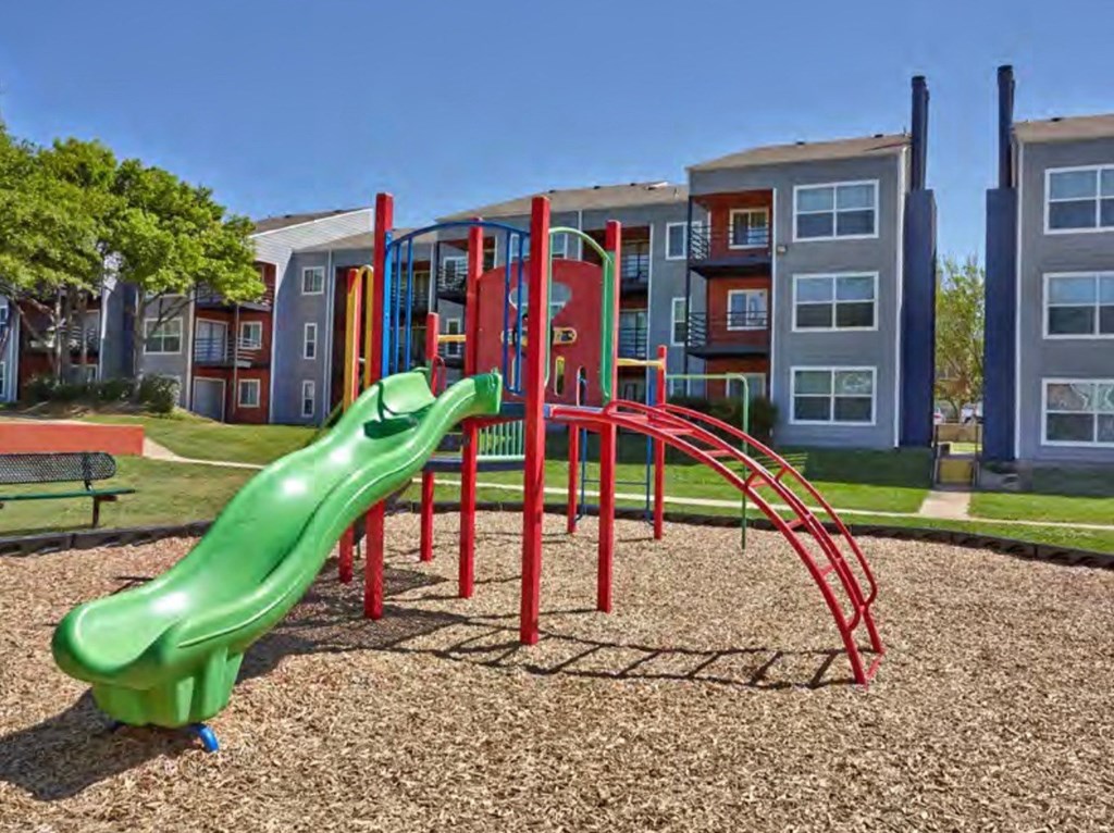 a playground with a slide in front of an apartment building