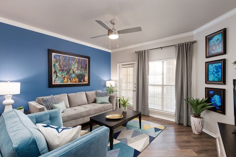 A living room with a blue couch and a painting on the wall.