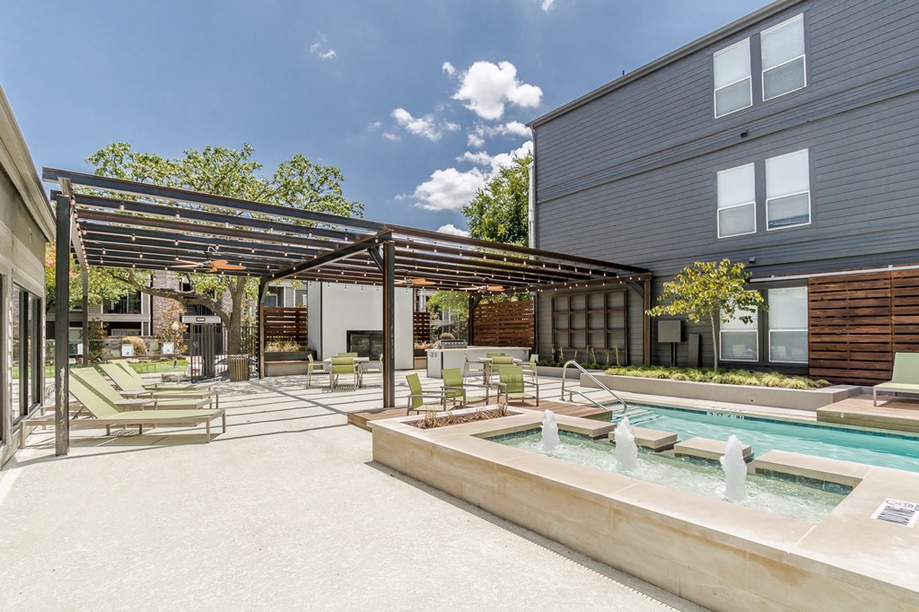 a patio with a hot tub and lounging chairs