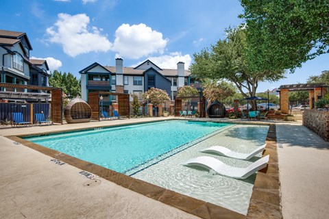 A swimming pool surrounded by a fence and chairs.