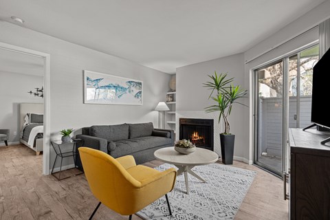 A living room with a yellow chair and a fireplace.