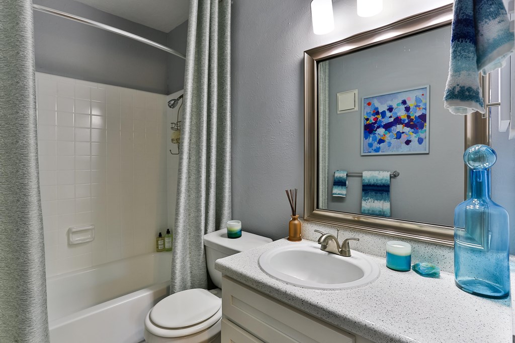 A bathroom with a white toilet, a sink, and a mirror.