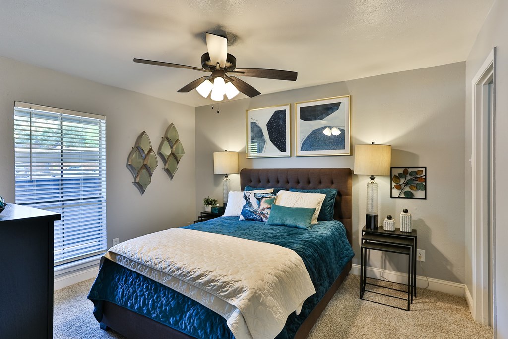 A bedroom with a bed, a ceiling fan, and a nightstand.