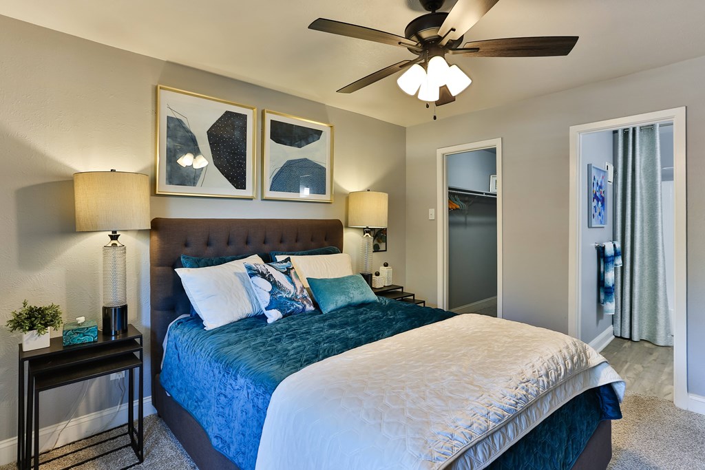 A bedroom with a bed, two lamps, and a ceiling fan.