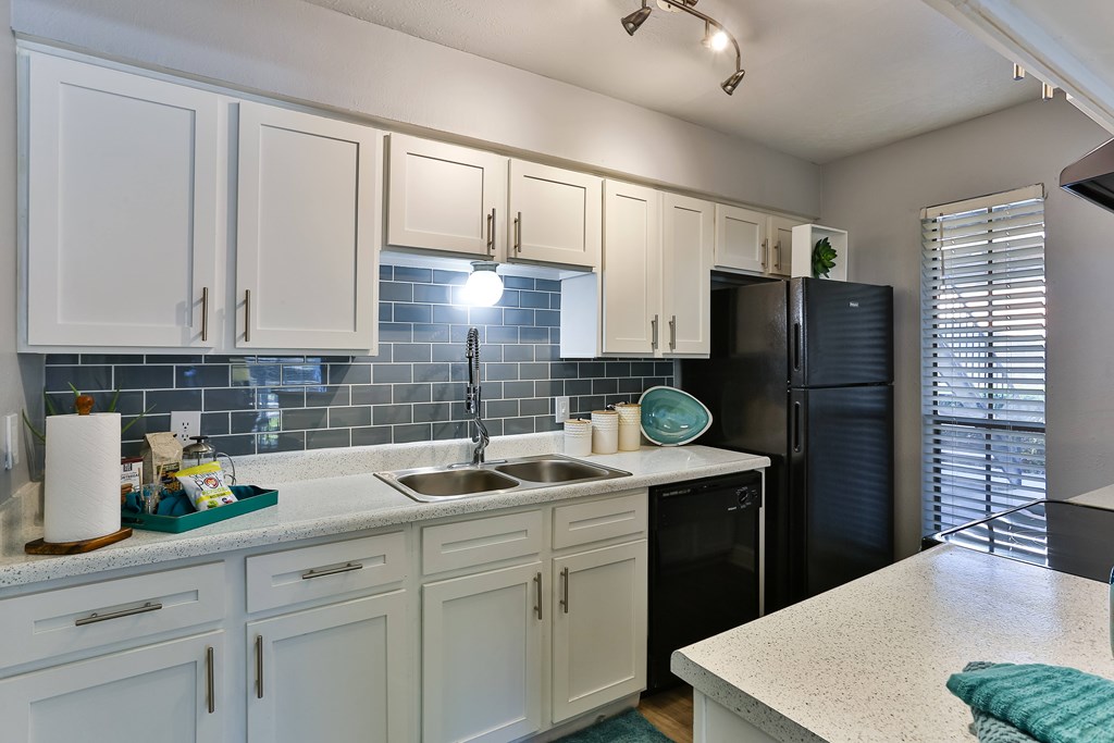 A kitchen with white cabinets and a black refrigerator.