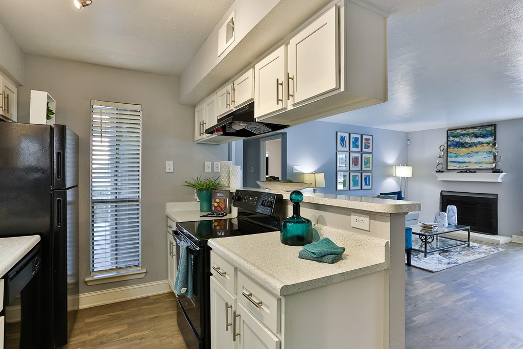A kitchen with black appliances and white cabinets.