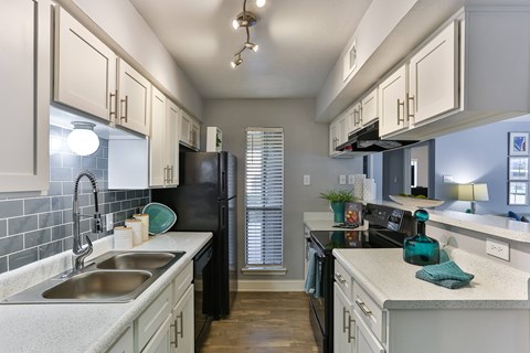 A kitchen with black appliances and white cabinets.
