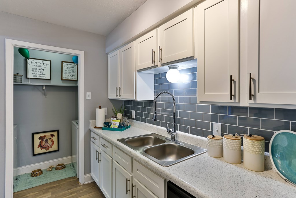 A kitchen with white cabinets and a blue tile backsplash.