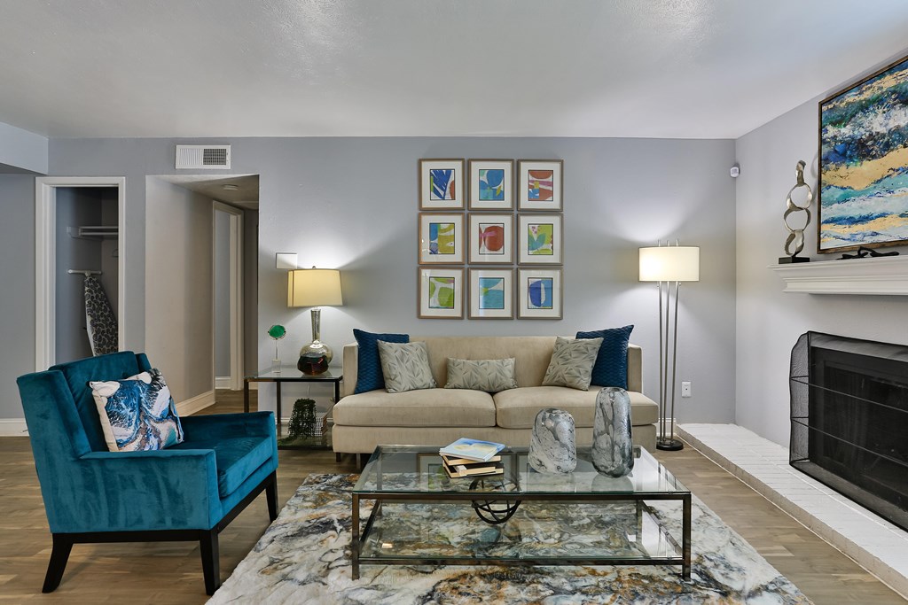 A living room with a blue chair and a glass coffee table.