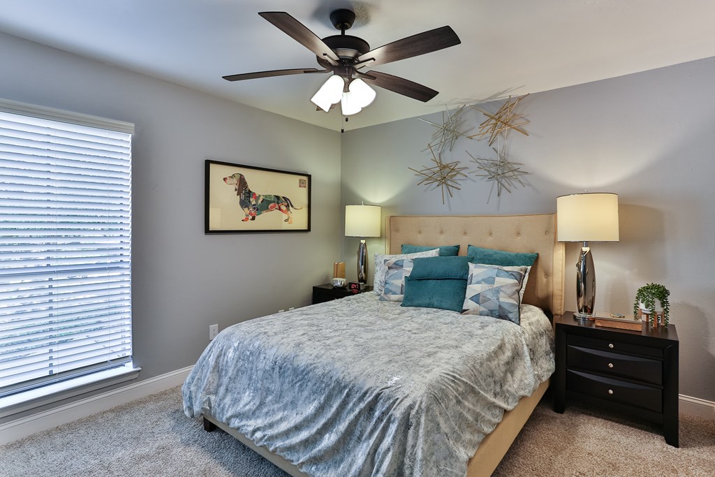 A bedroom with a bed, nightstand, and a ceiling fan.
