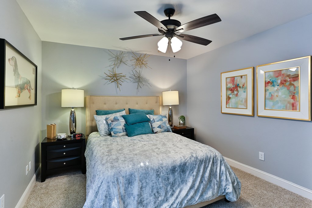 A bedroom with a bed, two lamps, and two framed pictures on the wall.