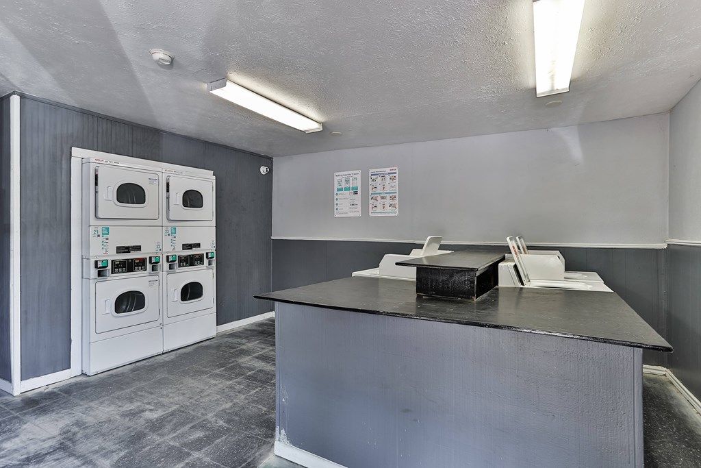 A room with a grey counter and a grey wall with a white oven.