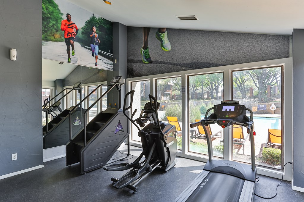 A home gym with a treadmill, stair climber, and elliptical trainer.