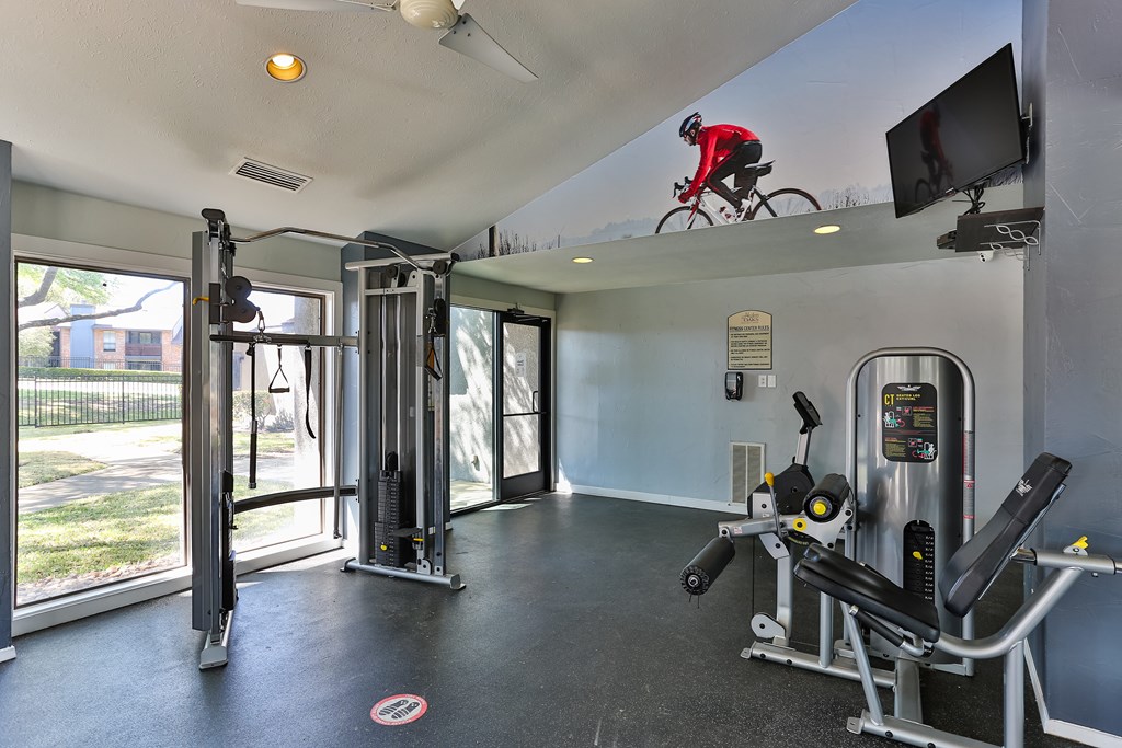 A gym with a television and a person on a bicycle above.