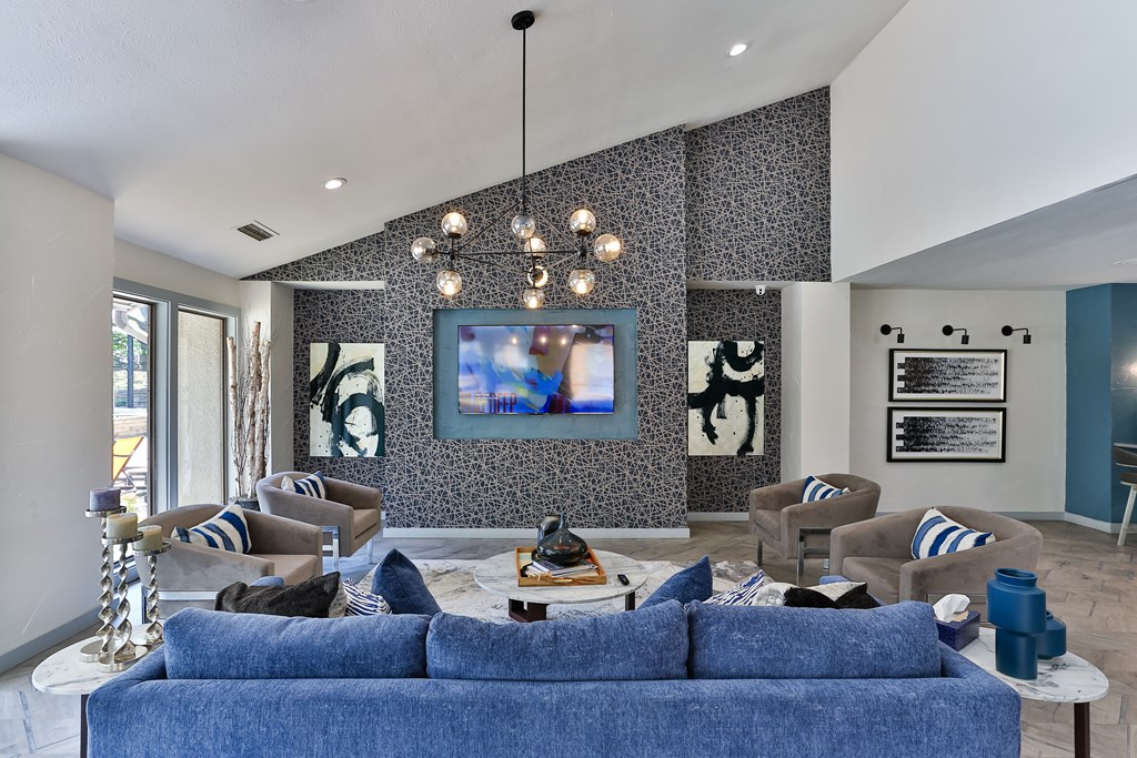 A living room with a blue couch and a painting on the wall.