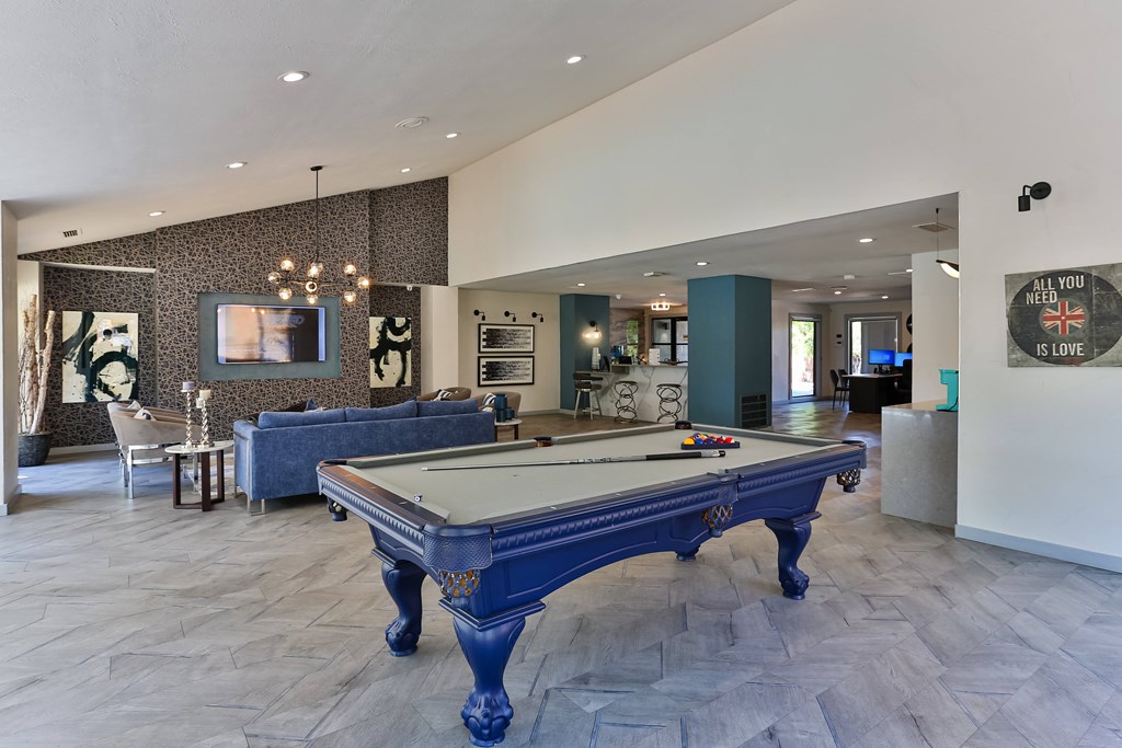 A pool table in a room with a blue couch and a painting on the wall.