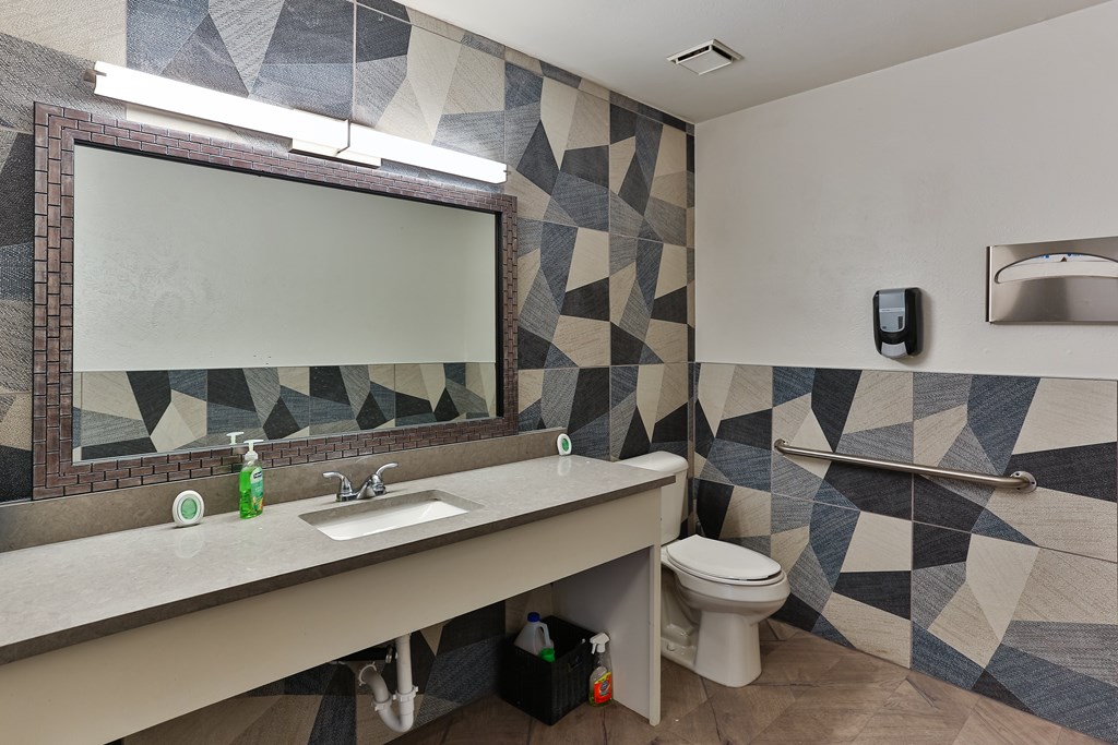 A bathroom with a sink, toilet, and mirror.
