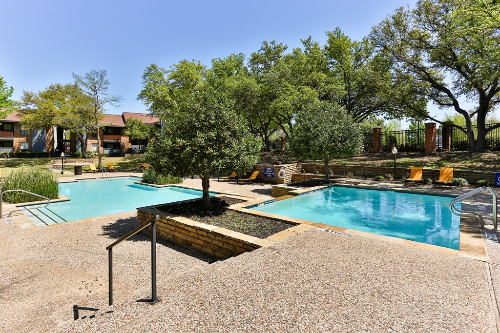 A pool surrounded by trees and a gravel area.