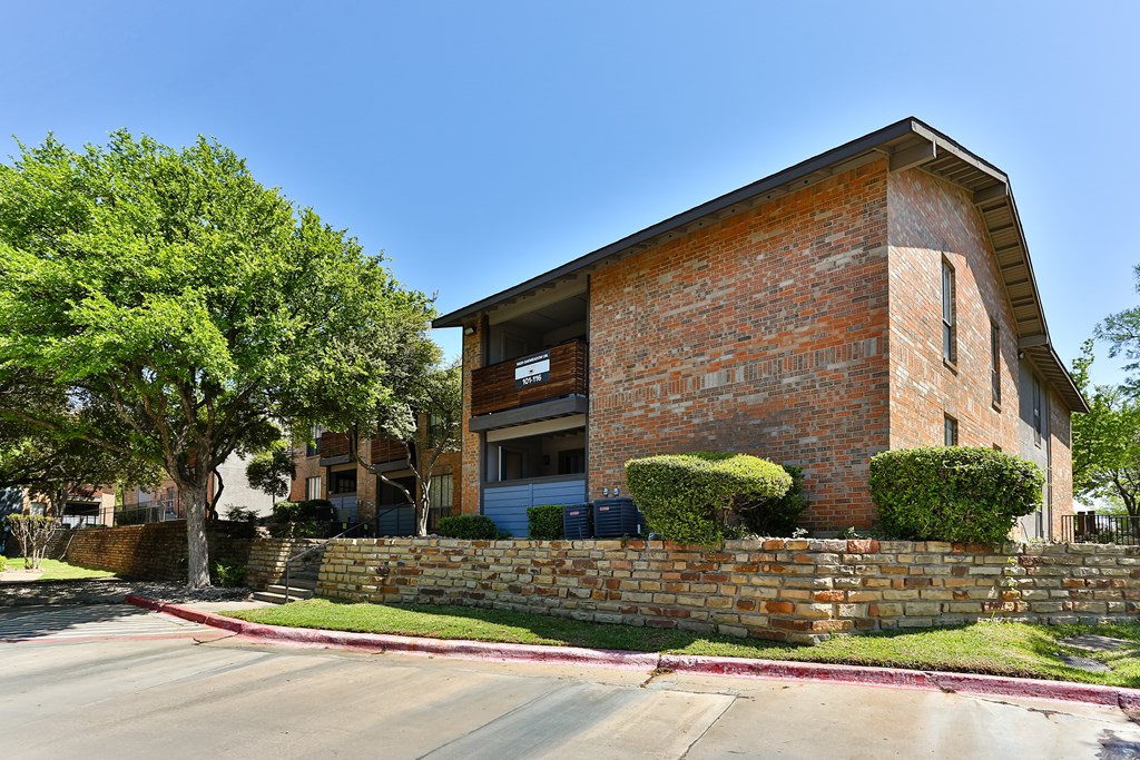 A brick building with a green tree in front.