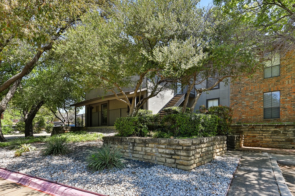 A house with a stone wall and a tree in front.