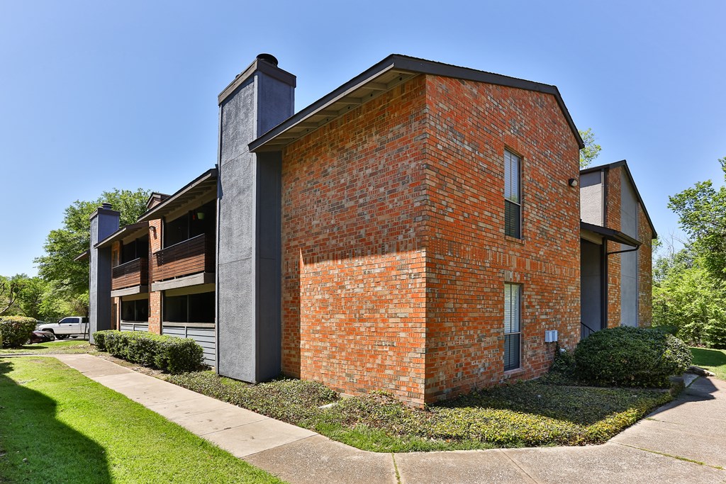 A red brick house with a grey roof and a small porch.