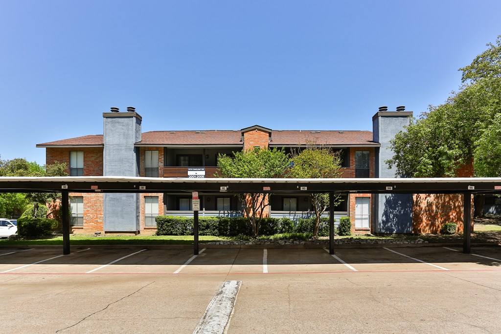 A parking lot in front of a building with a blue sky in the background.